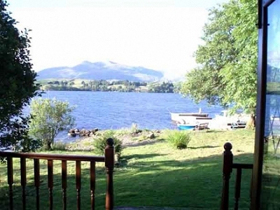 A view from the porch of an argyll chalet, looking over surrounding trees and loch