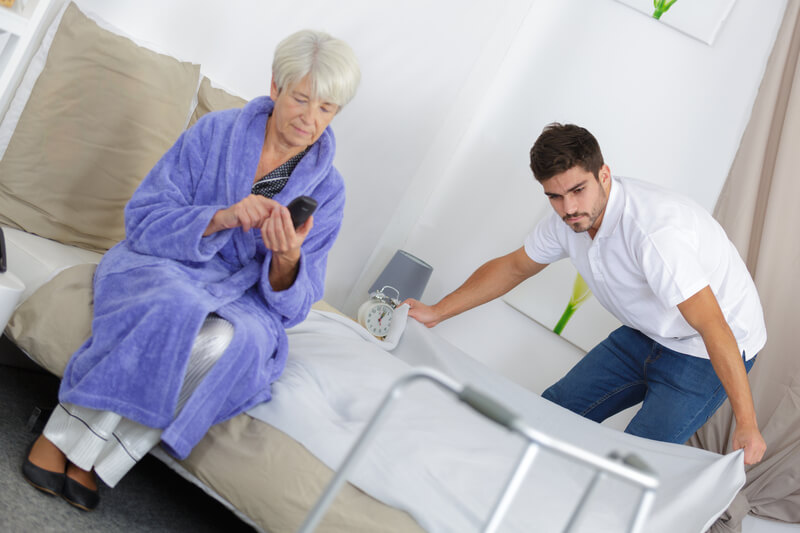 Carer making the bed for a old woman