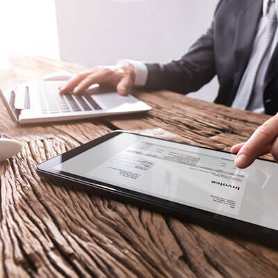 Close-up Of A Businessman`s Hand Working With Invoice On Digital Tablet
