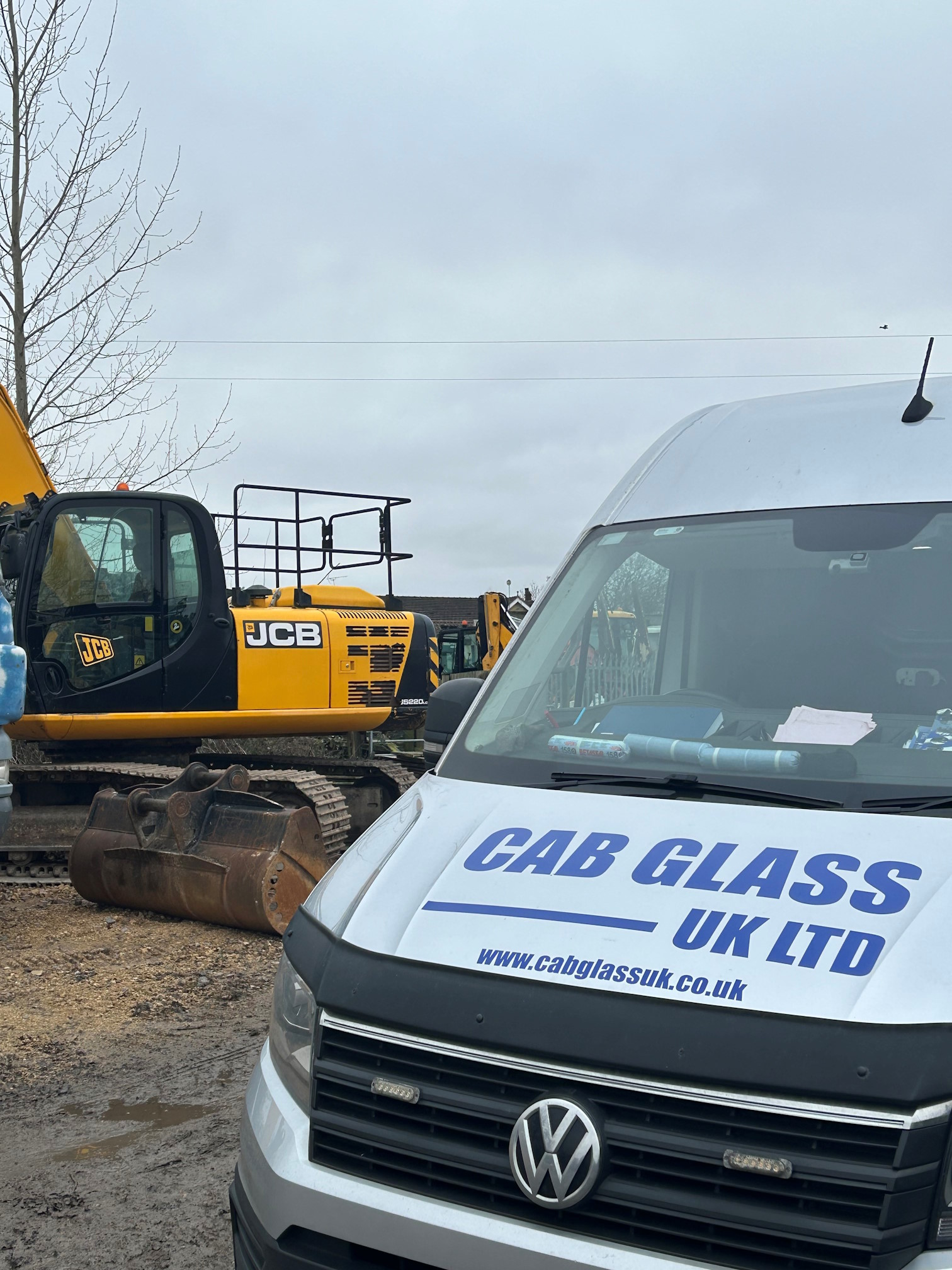 Cab Glass UK company van next to a digger
