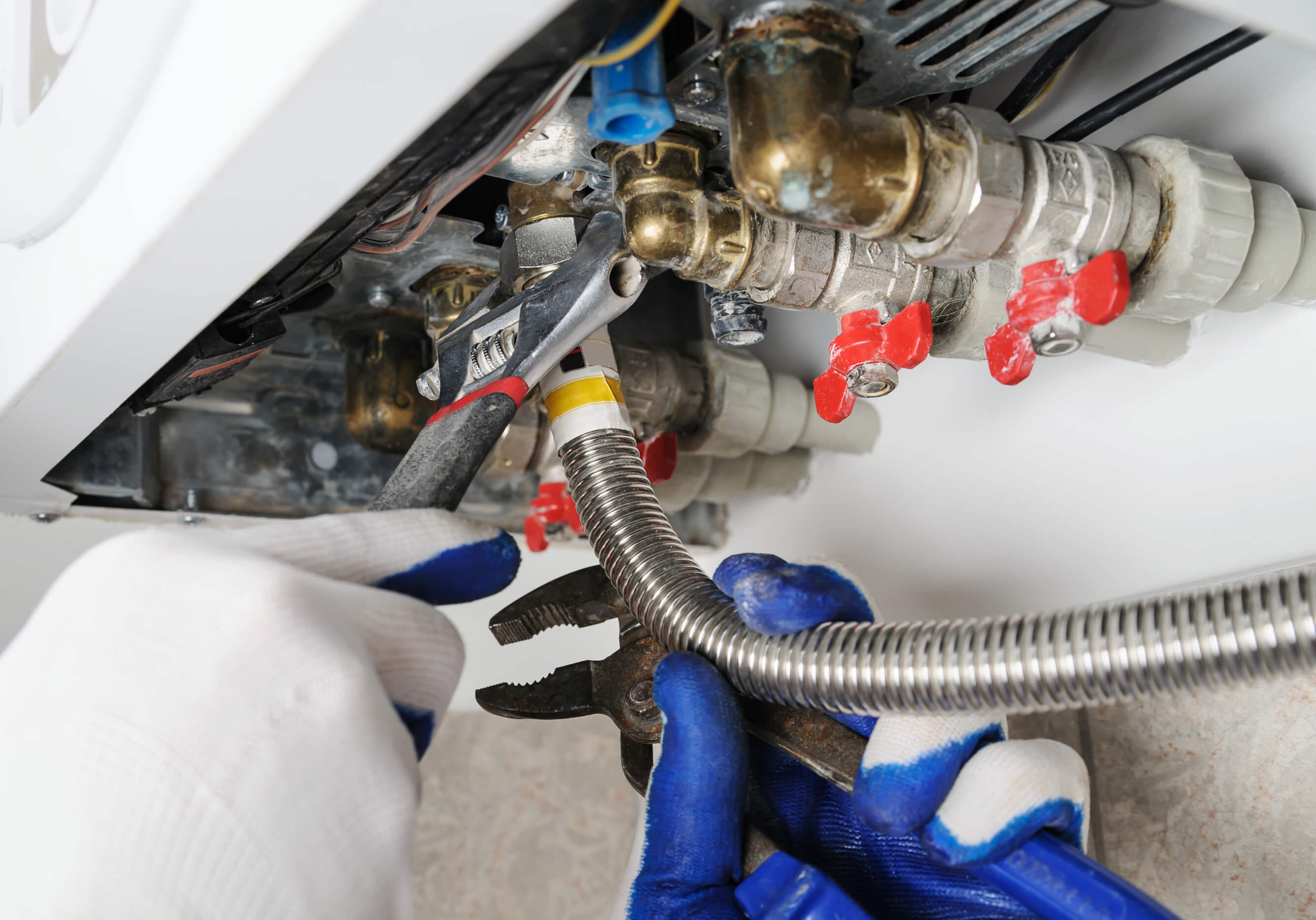 Plumber attaches to pipe gas boiler using adjustable wrench.