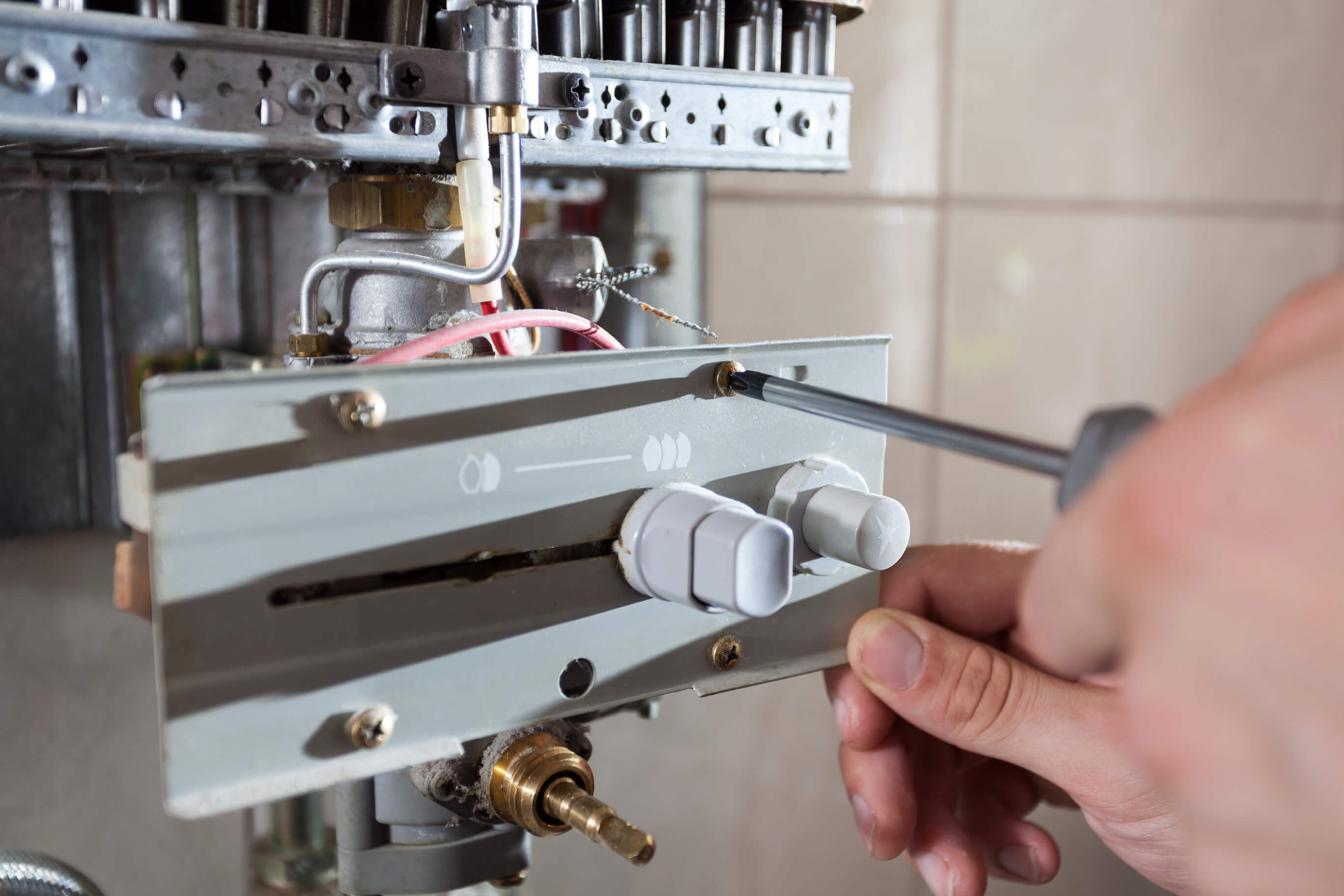 Plumber attaches to pipe gas boiler using adjustable wrench.