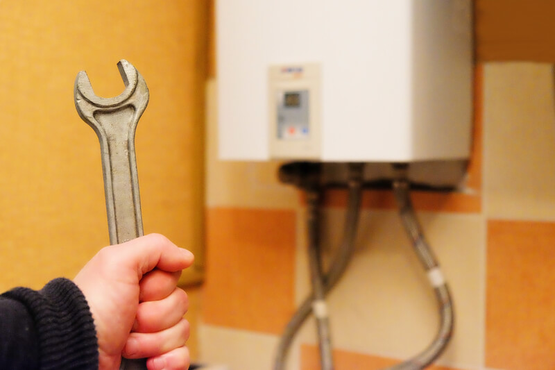 Male hand holding a wrench on the background gas boiler