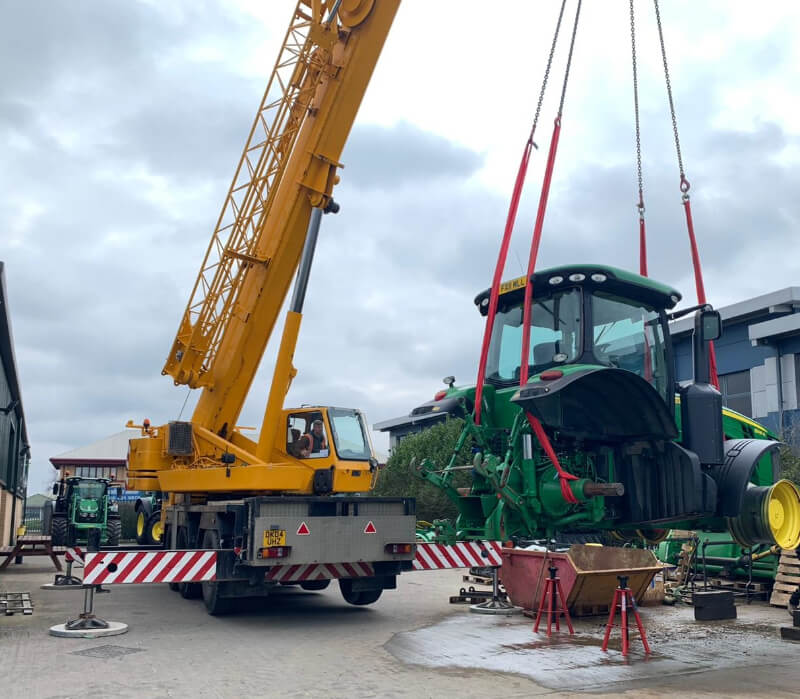 Crane Lifting a Green Tractor