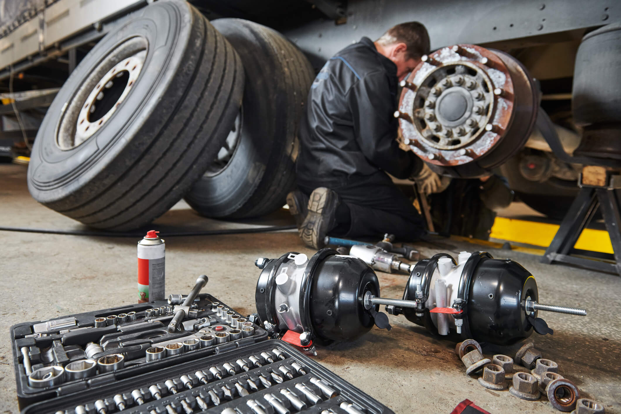 Person Inspecting under carriage of a vehicle with tools laid out in the foreground