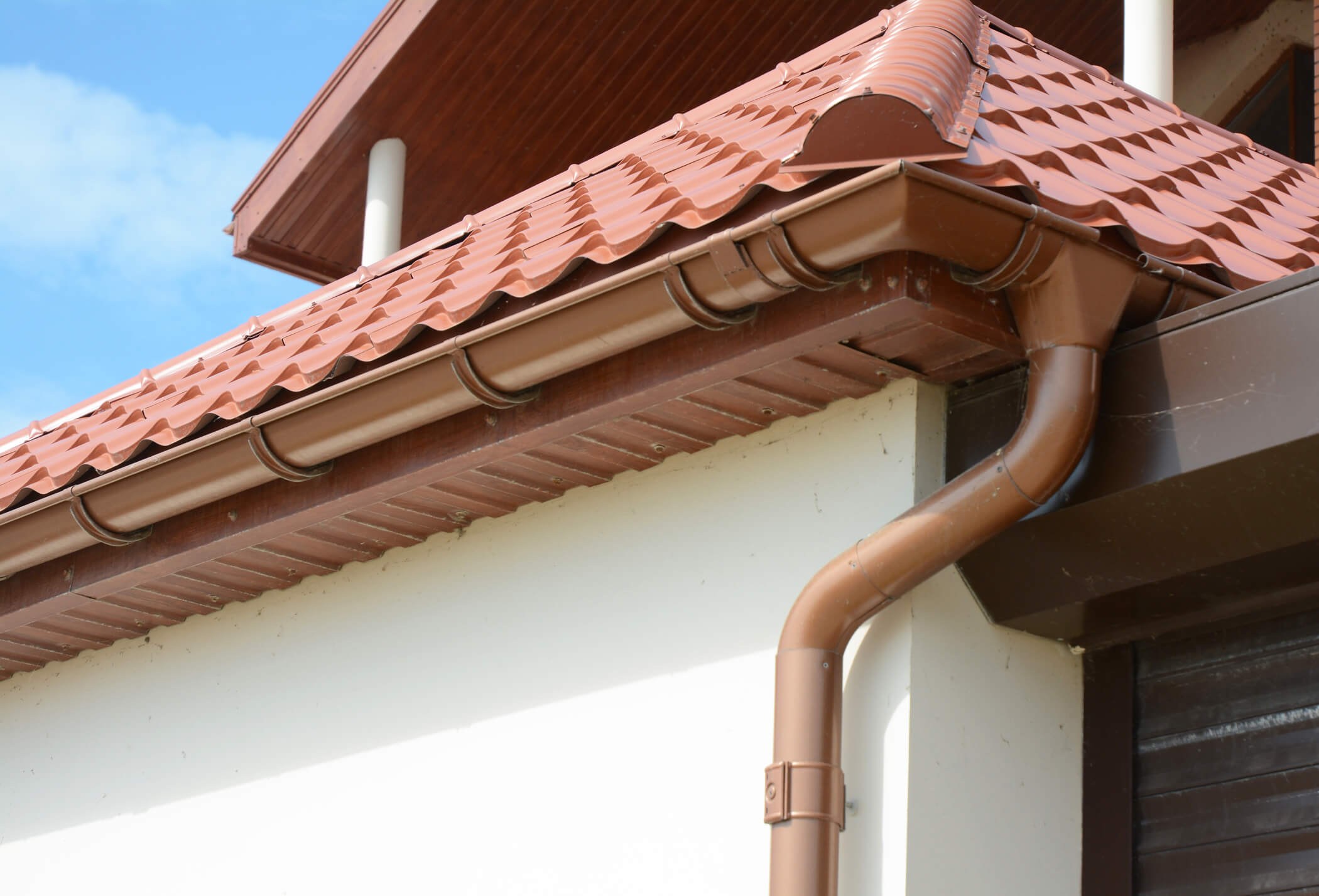 House attic metal roof with soffits, fascias, roof guttering, downspout gutter pipe.