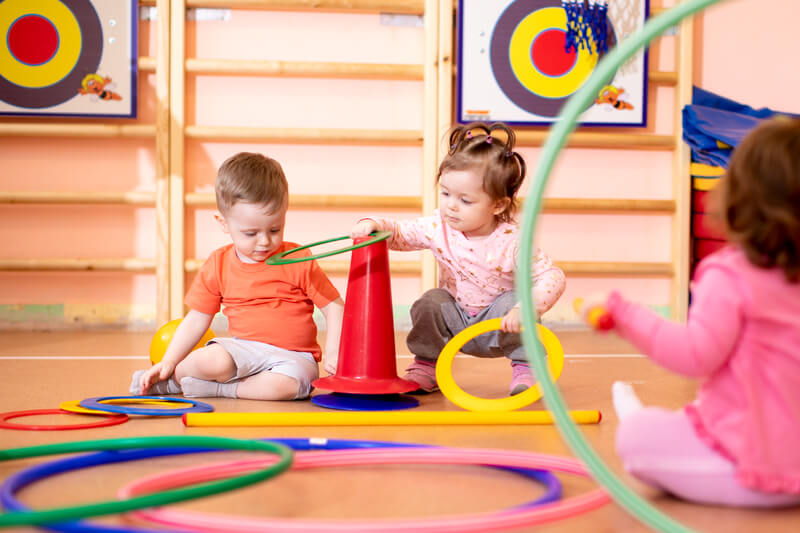 Nursery babies group play with rings in gym