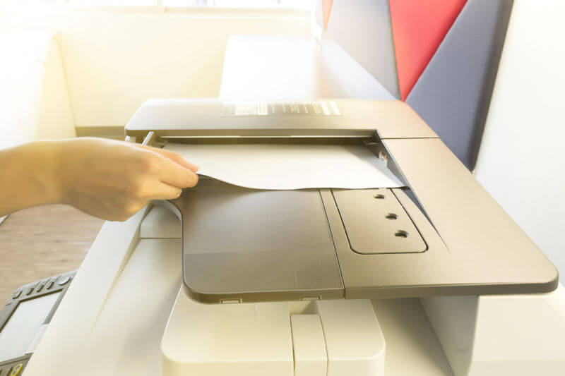 Man copying paper from Photocopier with access control for scanning key card