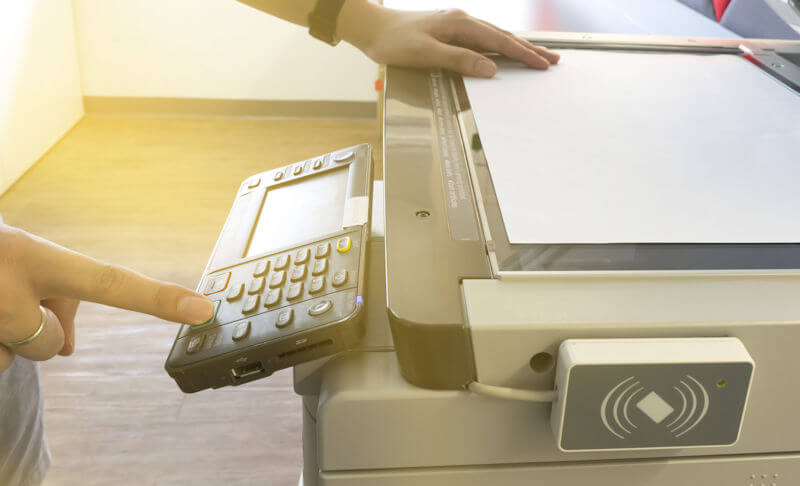 Man copying paper from Photocopier with access control for scanning key card