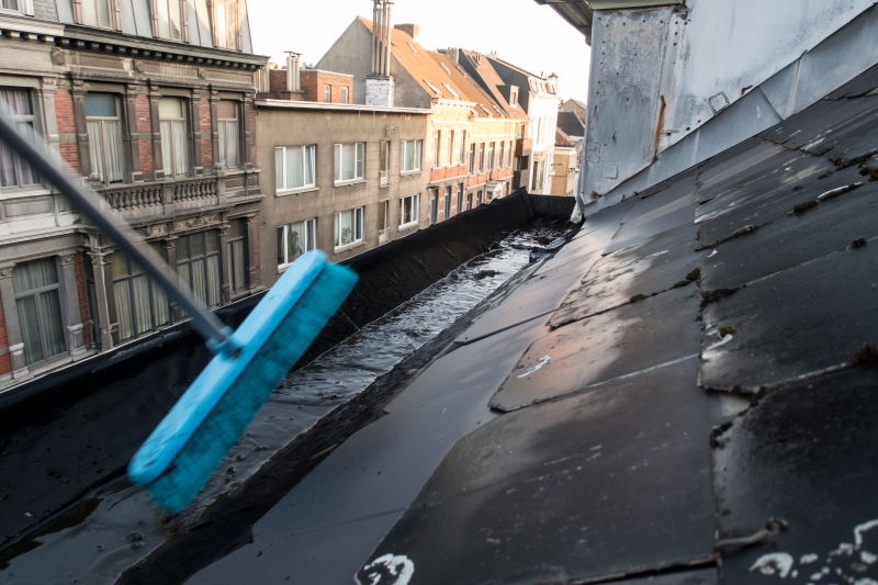 Gutter being cleaned with broom stick