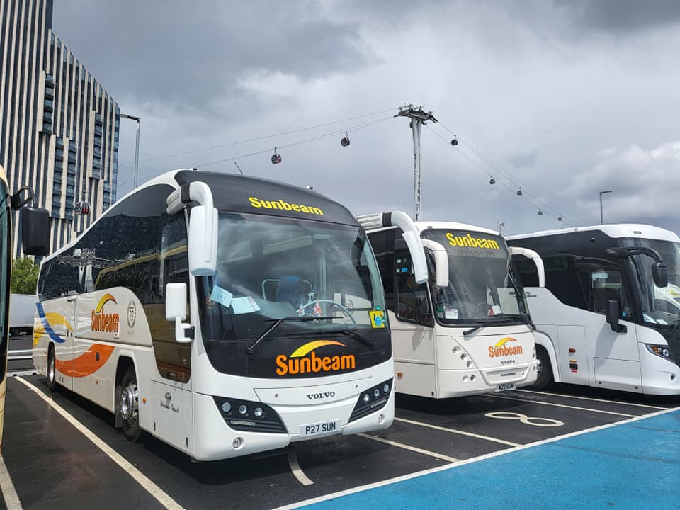 A large sunbeam coach and two mini-buses parked up