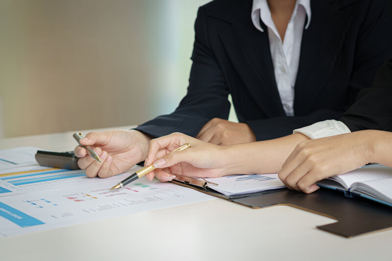 Business woman and partner hand pointing at finance chart for planning about tax