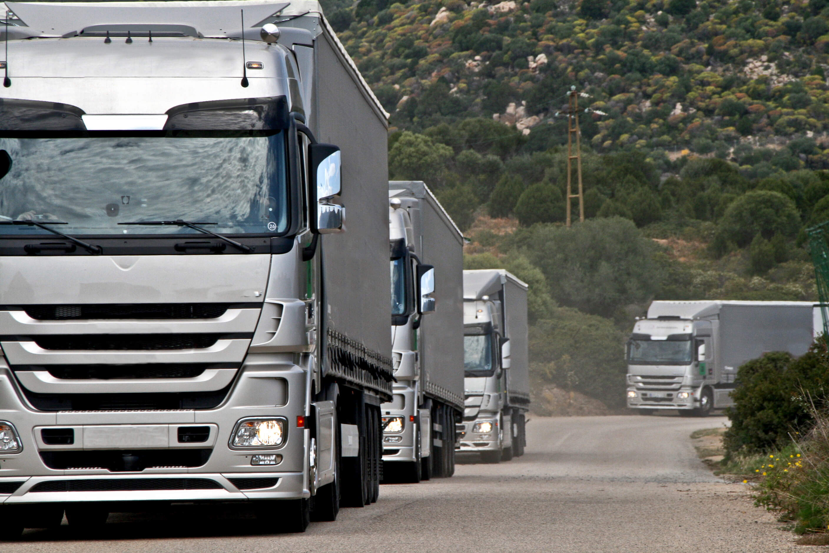 Silver trucks on long road.