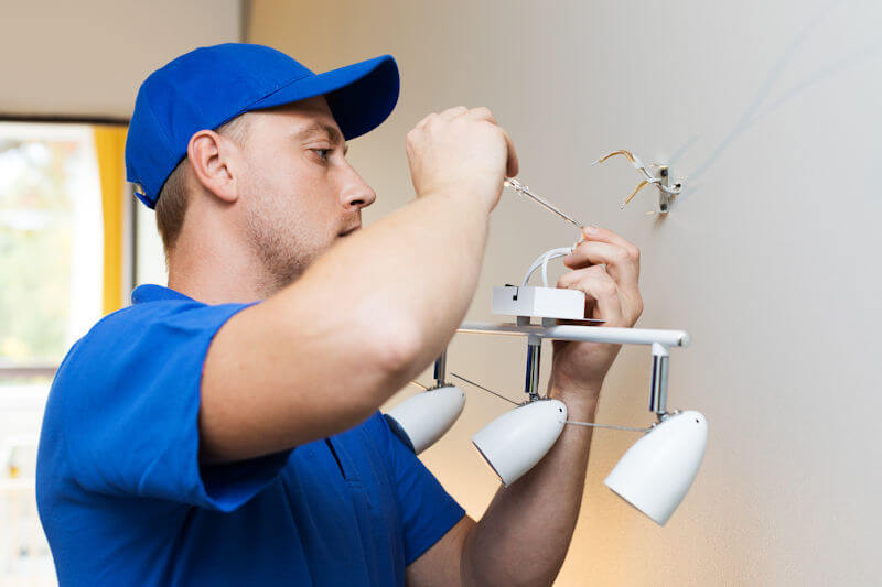 Electrician at work - installing lamp on the wall at home