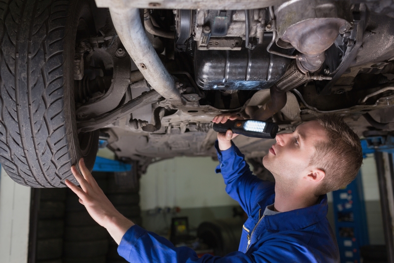 Mechanic inspecting underneath of car