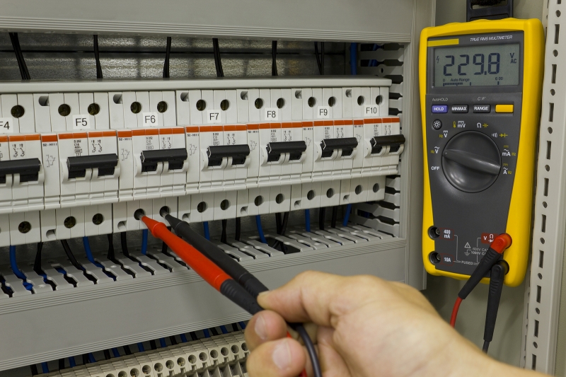 Electrician at work, measuring voltage in electrical cabinet