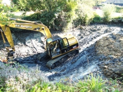 Excavator going in to the pond to reach more silt to be loaded away.