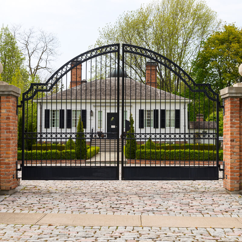 Metal wrought-iron gate and a house with nice landscaping