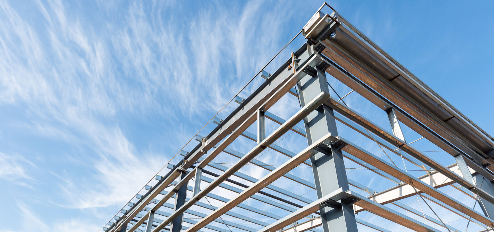 Steel frame workshop is under construction against a blue sky