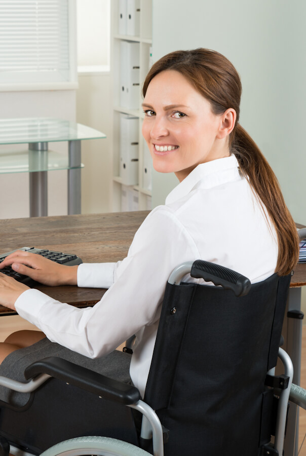 Young Happy Disabled Businesswoman On Wheelchair Using Computer In Office